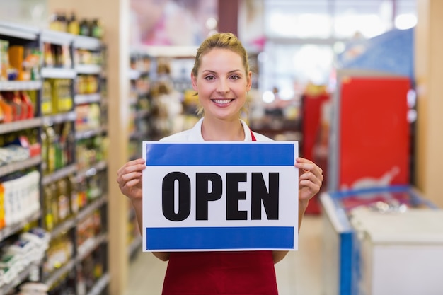 Portrait of a smiling blonde woman holding a sign