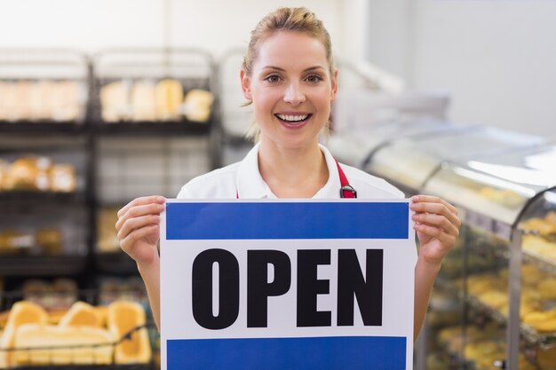 Portrait of a smiling blonde woman holding a sign 