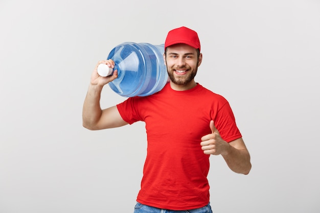 赤いtシャツとキャップでボトル入りの水配達宅配便を笑顔の肖像画