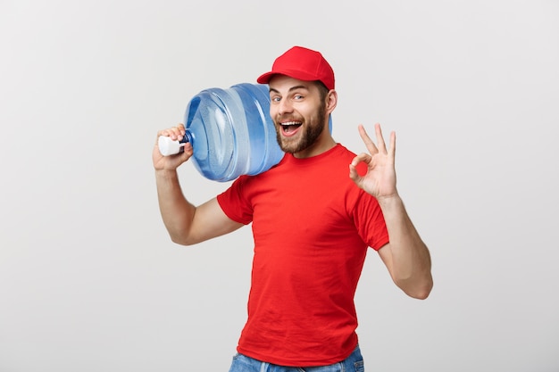 Portrait smiling bottled water delivery courier in red t-shirt and cap