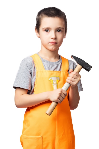 Portrait of a smiling boy carpenter in orange work overalls posing, holding a hammer in his hands having fun on a white isolated background. Children's costume for the holidays