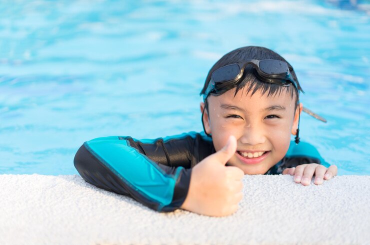 Photo スイミングプールで親指を上げている笑顔の男の子の肖像画