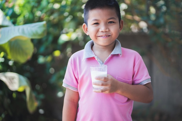 Portrait of smiling boy holding glass while standing outdoors