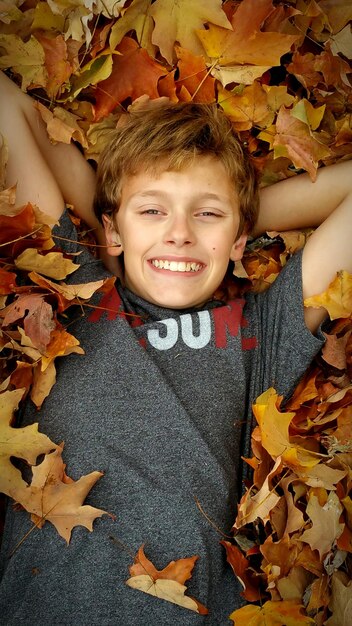 Portrait of smiling boy lying on autumn leaves