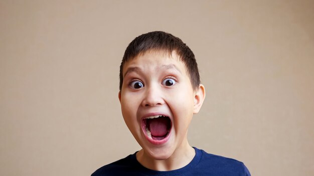 Portrait of smiling boy opening his mouth wide slow motion.