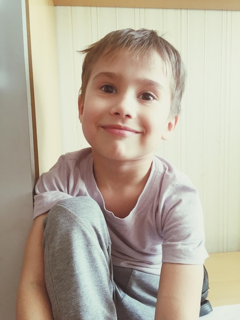 Photo portrait of smiling boy sitting at home