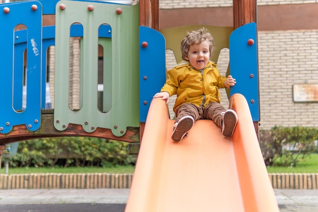 Photo portrait of smiling boy sitting on slide at playground