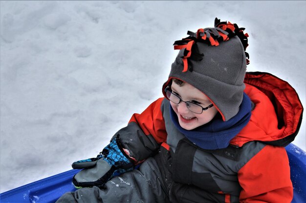 Portrait of smiling boy on snow against sky