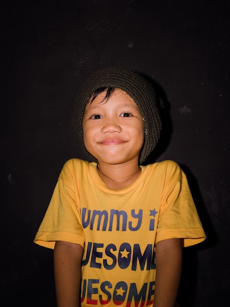 Foto ritratto di un ragazzo sorridente in piedi su uno sfondo nero