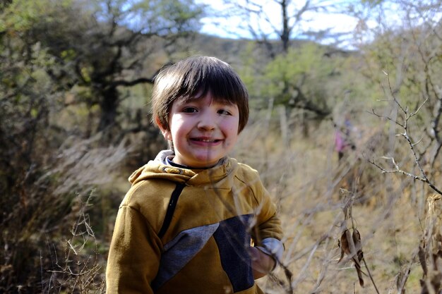 Photo portrait of smiling boy standing in forest