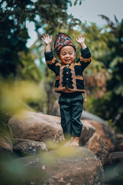 Photo portrait of smiling boy standing on rock