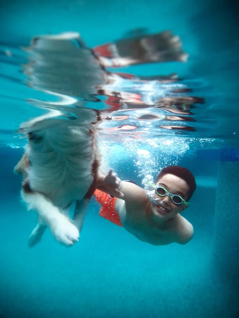 Portrait of smiling boy with dog swimming in pool