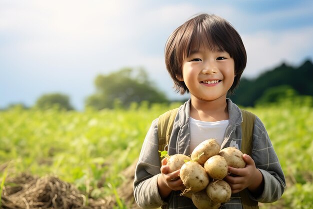 Портрет улыбающегося мальчика с свежо выкопанными картошками на поле при закате