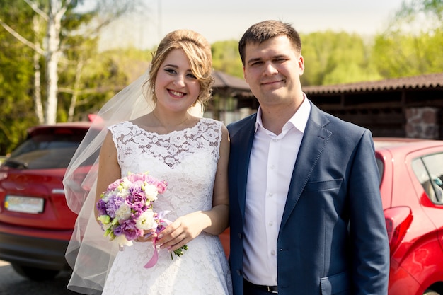 Portrait of smiling bride and groom posing at sunny day at park