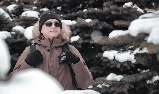 Ritratto sorridente brutale giovane all'aria aperta tra gli alberi di natale innevati