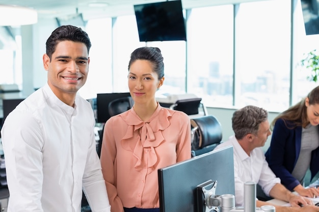 Portrait of smiling business colleagues standing together at desk