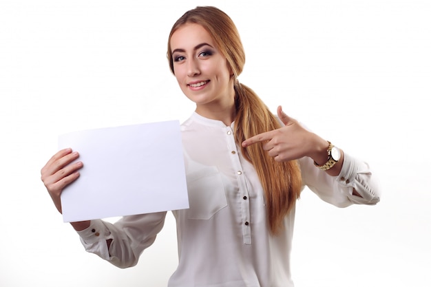 Portrait of smiling business woman with finger shows on paper, isolated on white wall