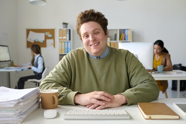 Portrait of smiling businessman looking at camera while having video call on computer sitting in office