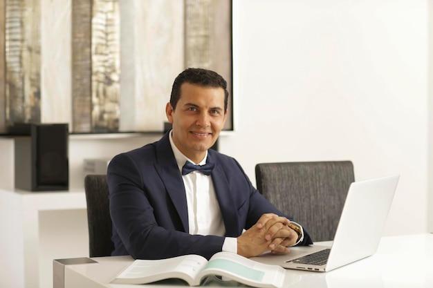 Photo portrait of smiling businessman using laptop at office