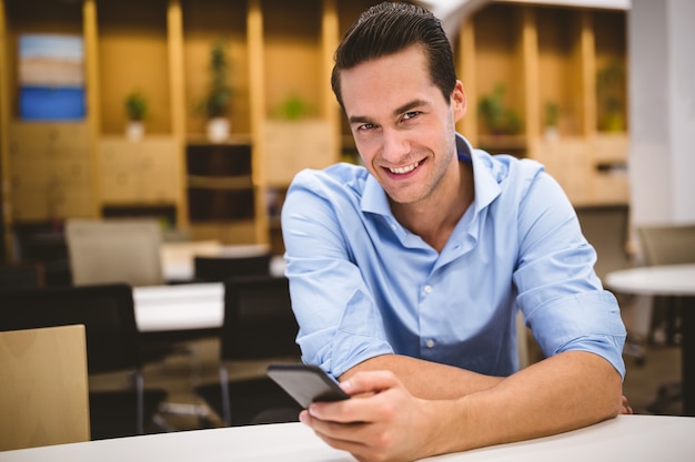 Ritratto dell'uomo d'affari sorridente che per mezzo del telefono