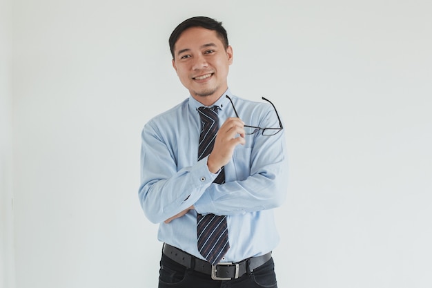 Portrait of smiling businessman wearing blue shirt and tie holding glasses at camera