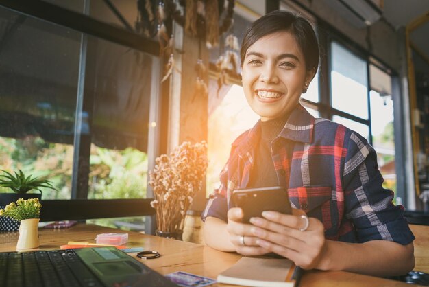 Photo portrait of smiling businesswoman holding mobile phone at desk