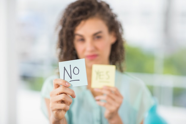 Photo portrait of a smiling businesswoman holding yes and no sticks