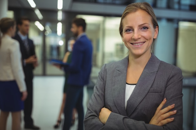 Portrait of smiling businesswoman standing with arms crossed