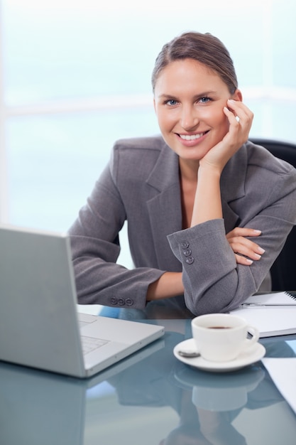 Ritratto di una donna d'affari sorridente che lavora con un notebook