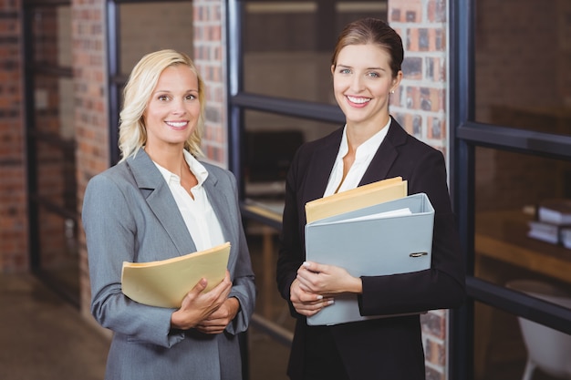 Portrait of smiling businesswomen holding documents 