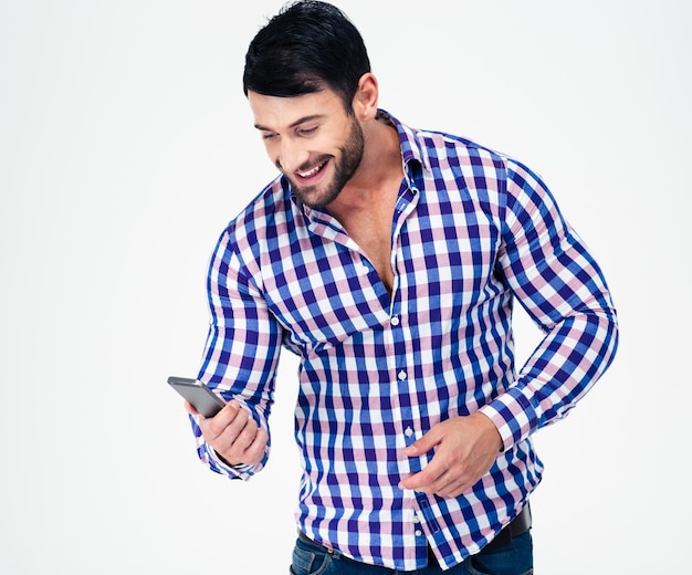 Portrait of a smiling casual man using smartphone isolated on a white wall