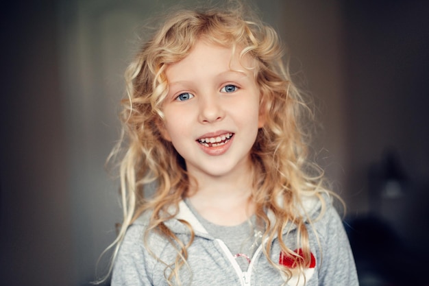 Portrait of smiling caucasian blonde girl with long messy hair missing lost milk tooth