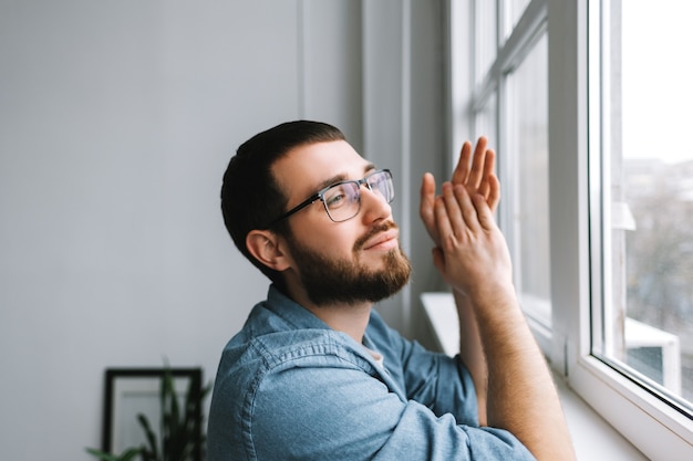 Portrait of smiling caucasian dreaming man looking outside in window .