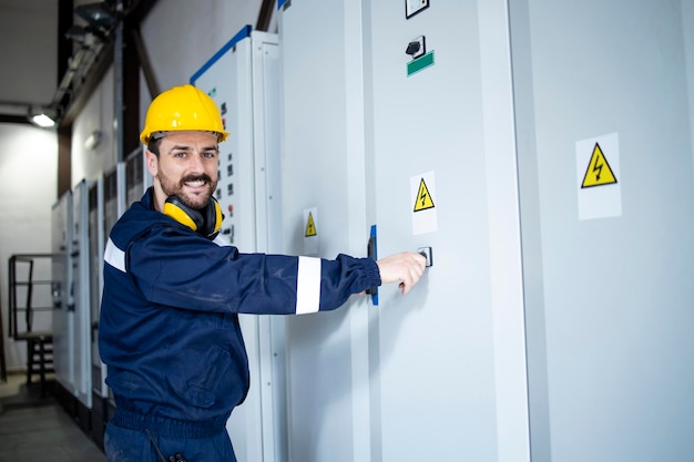 Portrait of smiling caucasian electrics standing by electrical cabinets