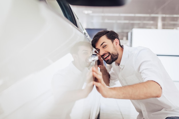 Portrait of smiling caucasian man looking at new car in dealership salon