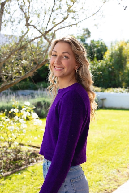 Portrait of smiling caucasian woman standing in sunny garden looking to camera