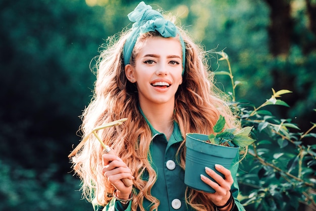 Portrait of smiling charming girl hold flower pot and looking at camera spring woman