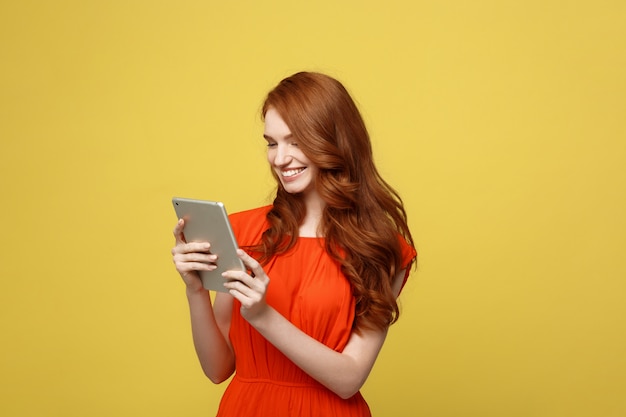 Portrait of smiling charming redhead young woman with working on tablet