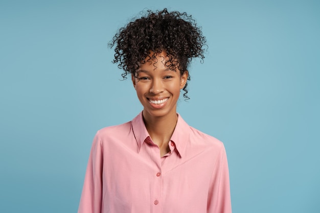 portrait of smiling cheerful woman with wavy hair looking at camera standing isolated