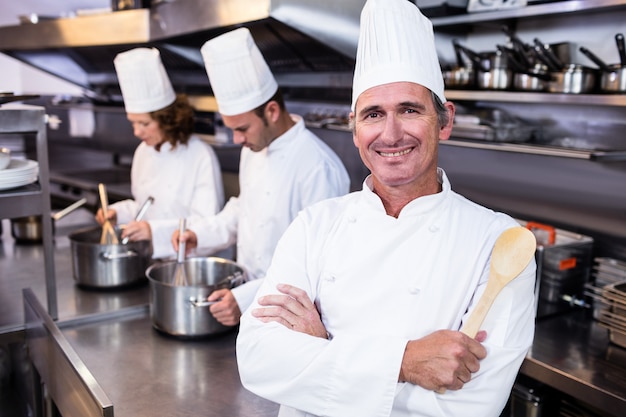 Портрет улыбающегося шеф-повара в коммерческих кухне