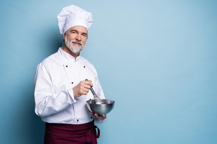 Photo portrait of smiling chef holding bowl and wire whisk on blue background chef making meal