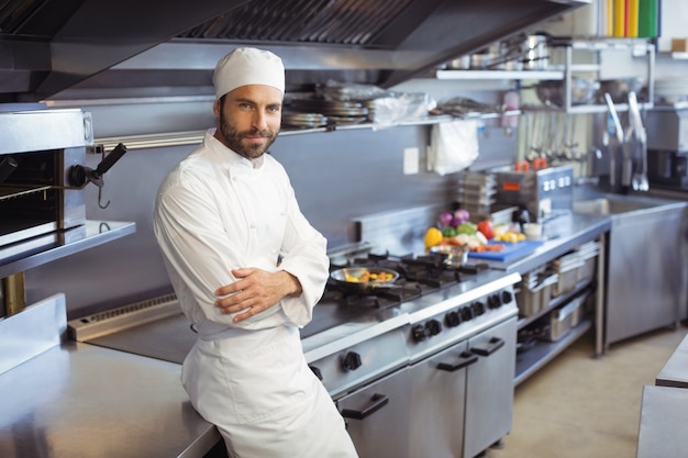 Portrait of smiling chef standing with arms crossed in commercial kitchen