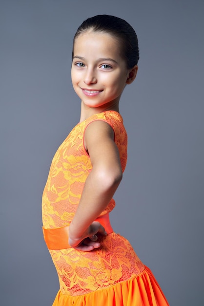 Portrait of smiling child girl posing looking at camera on gray background