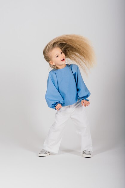 Portrait smiling child girl with flying blond hair, studio