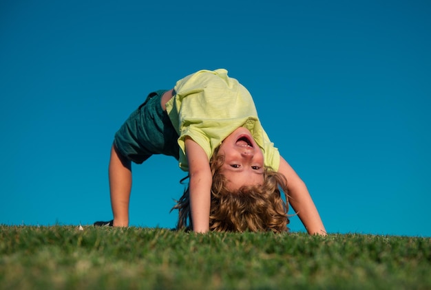 Portrait of a smiling child upside down on green grass cute kid boy enjoying nature outdoors healthy