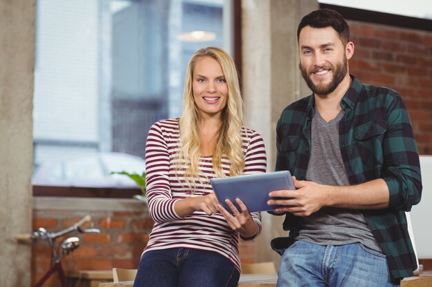 Portrait of smiling colleagues using tablet 