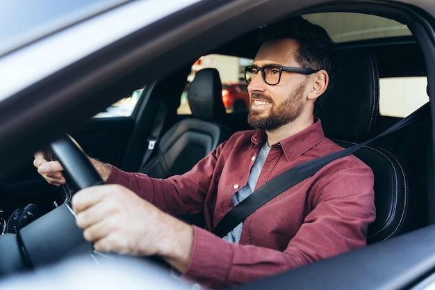 Portrait of smiling confident bearded man driver wearing eyeglasses driving car looking away
