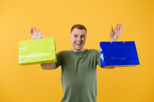 Portrait of smiling couple holding shopping bags isolated on yellow background