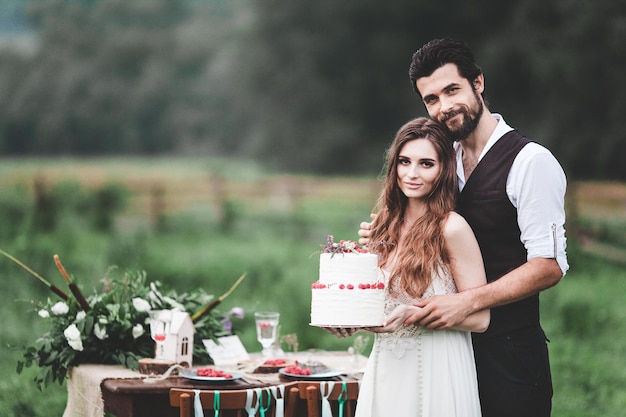 Photo portrait of smiling couple holding wedding cake at farm