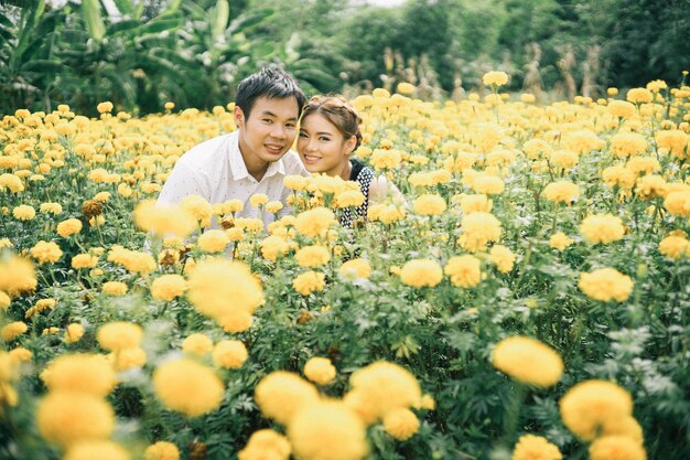 Photo portrait of smiling couple standing amidst yellow flowers